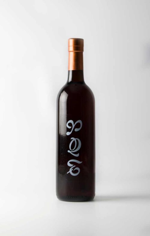 Fotografia d'una botella negra amb tipografia blanca i la part de dalt d'un color bronze.