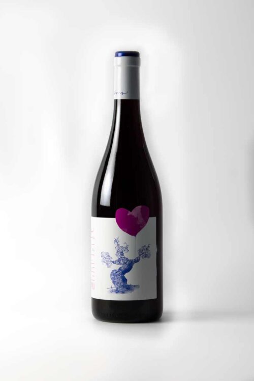 Fotografia de la botella de vi blanc, etiqueta blanca amb un dibuix amb línia blava i un cor amb taca lila.